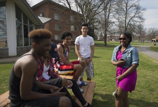 Students laughing at campus picnic tables in Spring 068